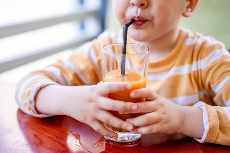 Bambino che beve succo di frutta