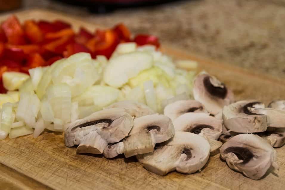 Funghi, cipolle e peperoni su tagliere di legno