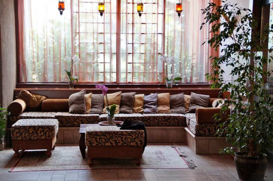 Zona relax in casa con divano ergonomico, cuscini morbidi, lampade soffuse e piante naturali.