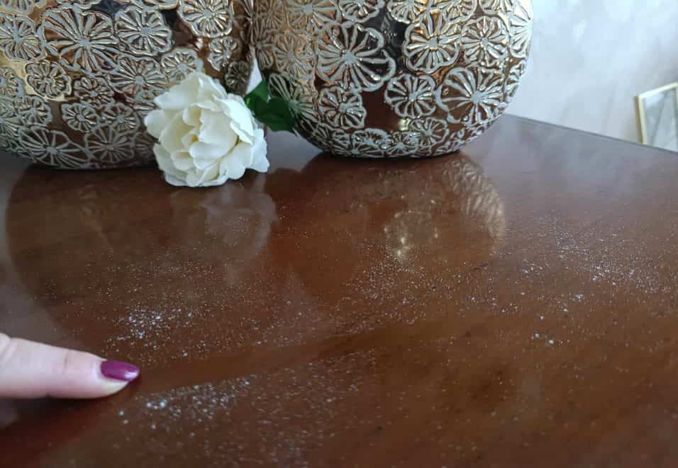 Panno in microfibra che pulisce una mensola con una miscela antistatica fai-da-te per prevenire l'accumulo di polvere.