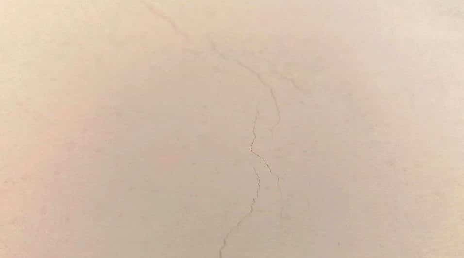 Un muro di casa con crepe riparate in modo professionale con stucco e vernice traspirante.