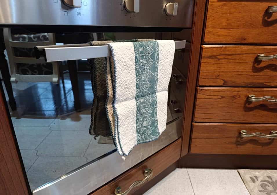 Strofinaccio appeso sulla maniglia del forno in una cucina, evidenziando i rischi di contaminazione batterica