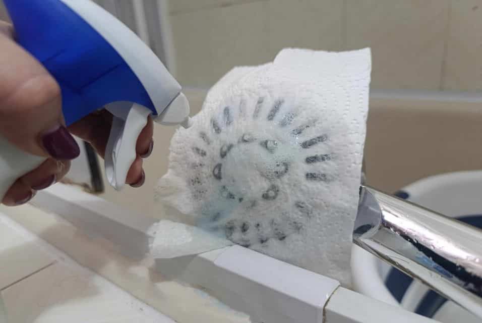 Soffione della doccia avvolto in scottex con anticalcare applicato per rimuovere il calcare