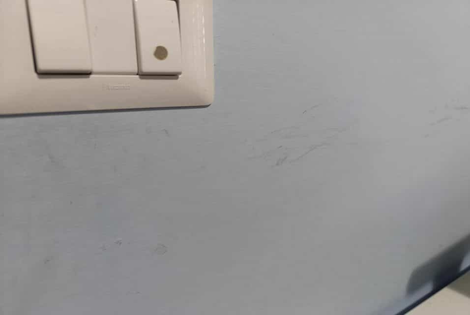 Pareti di casa con macchie di pennarello e sporco, in fase di pulizia con un panno e prodotti naturali